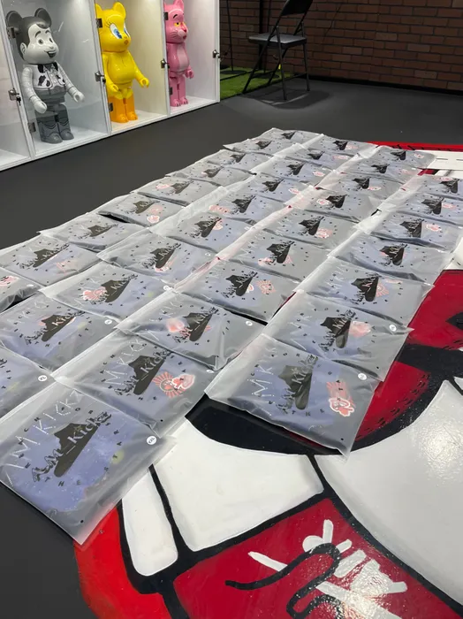 Custom poly mailers with a unique print are laid out across a floor displaying oversized graphic art, suggesting a creative or branding-focused context.